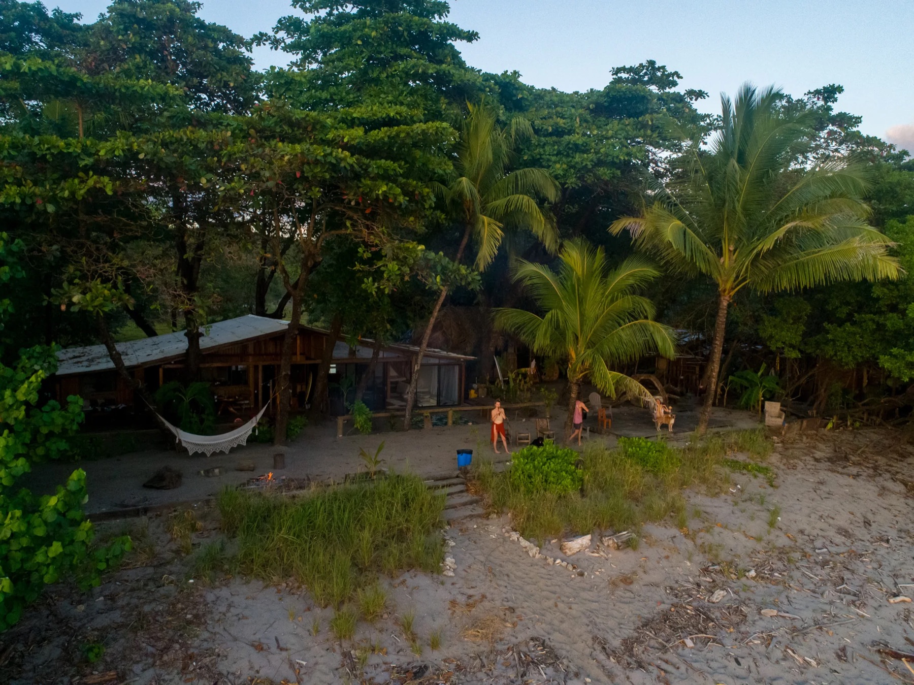 House of Waves seen from above at dusk: the beach house, a hammock and the gathering place by the sand